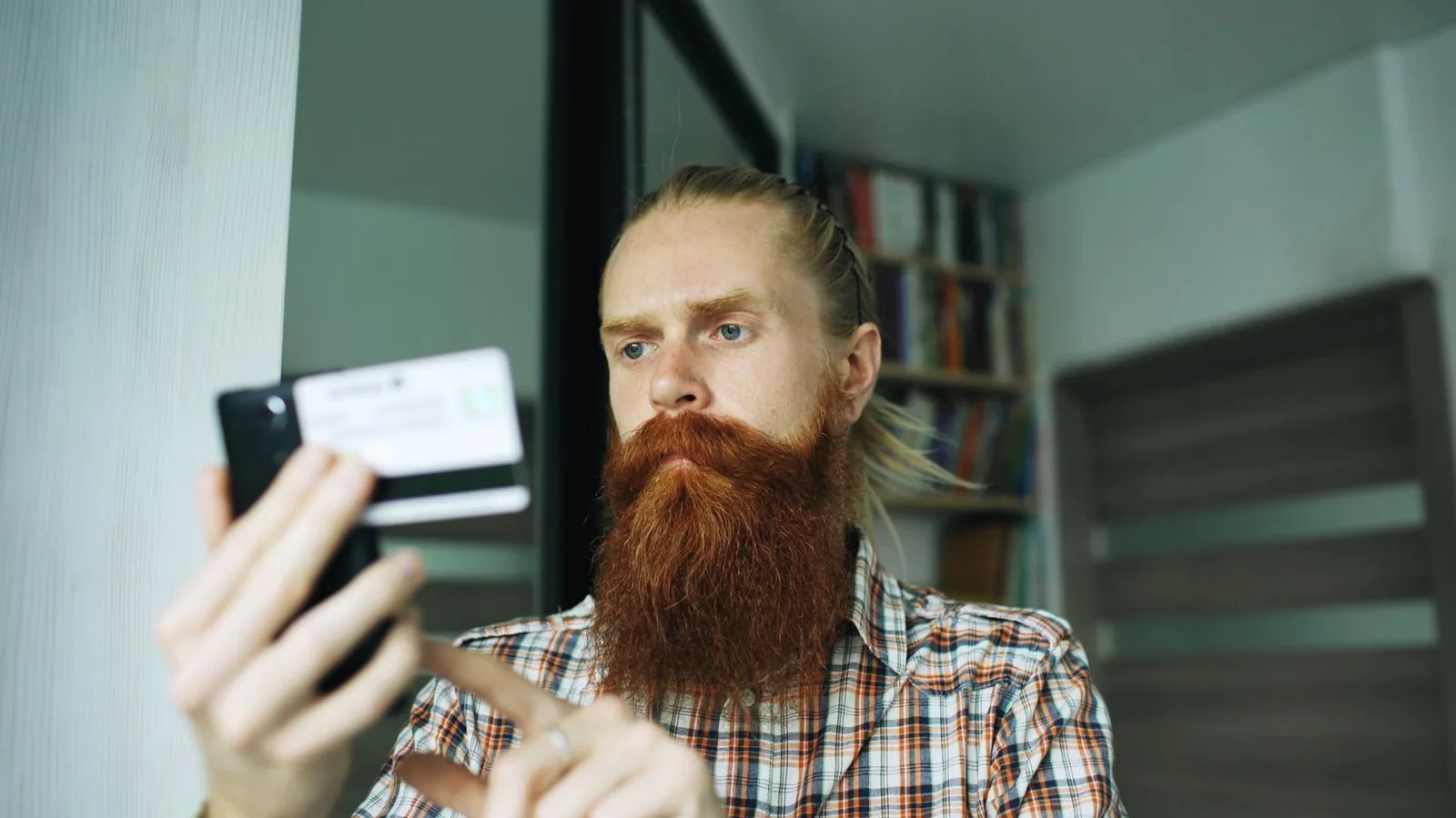 Homme tenant un smartphone et une carte bancaire devant lui