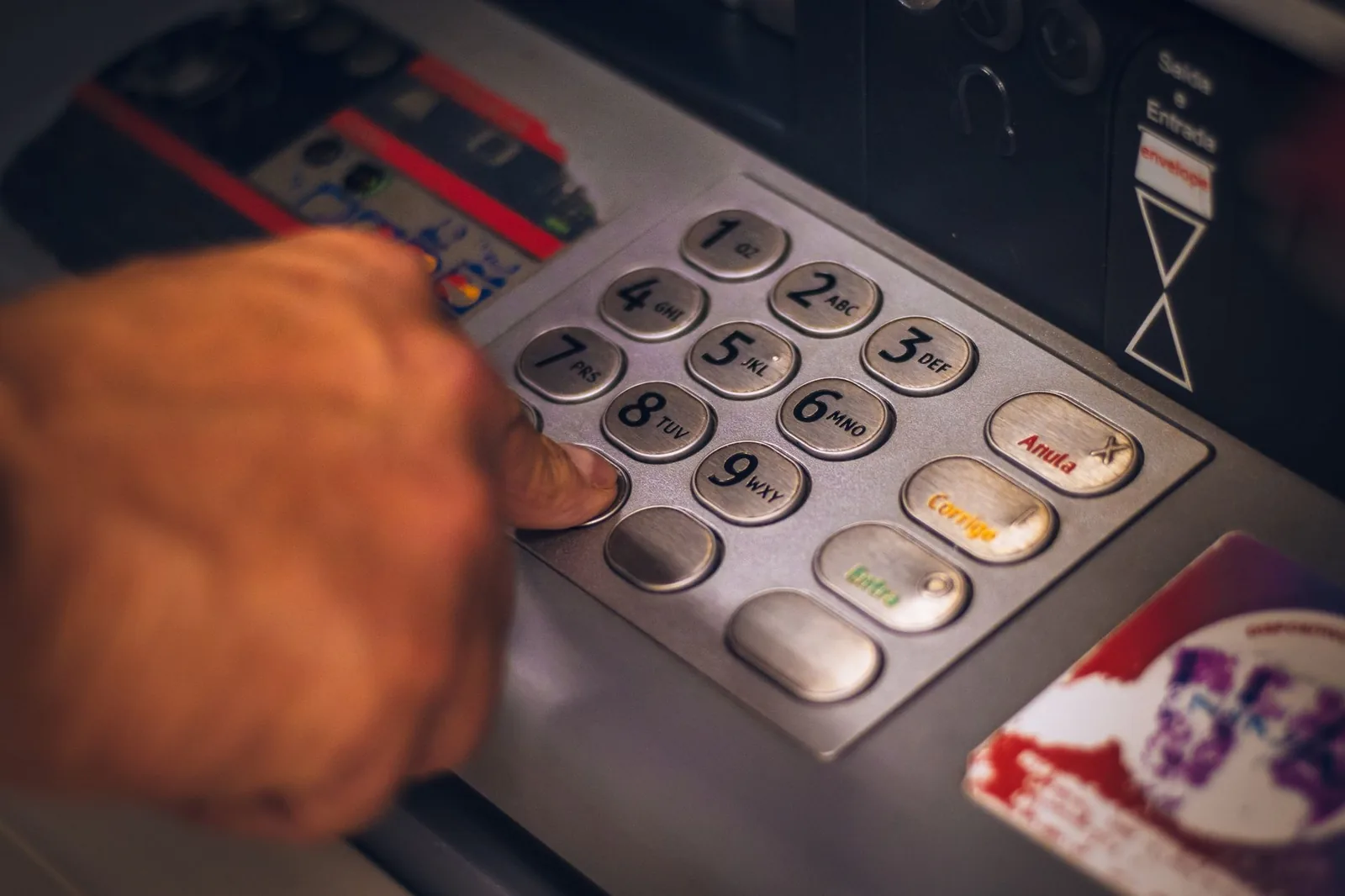 Main sur le clavier d’un distributeur automatique de billets pendant un retrait