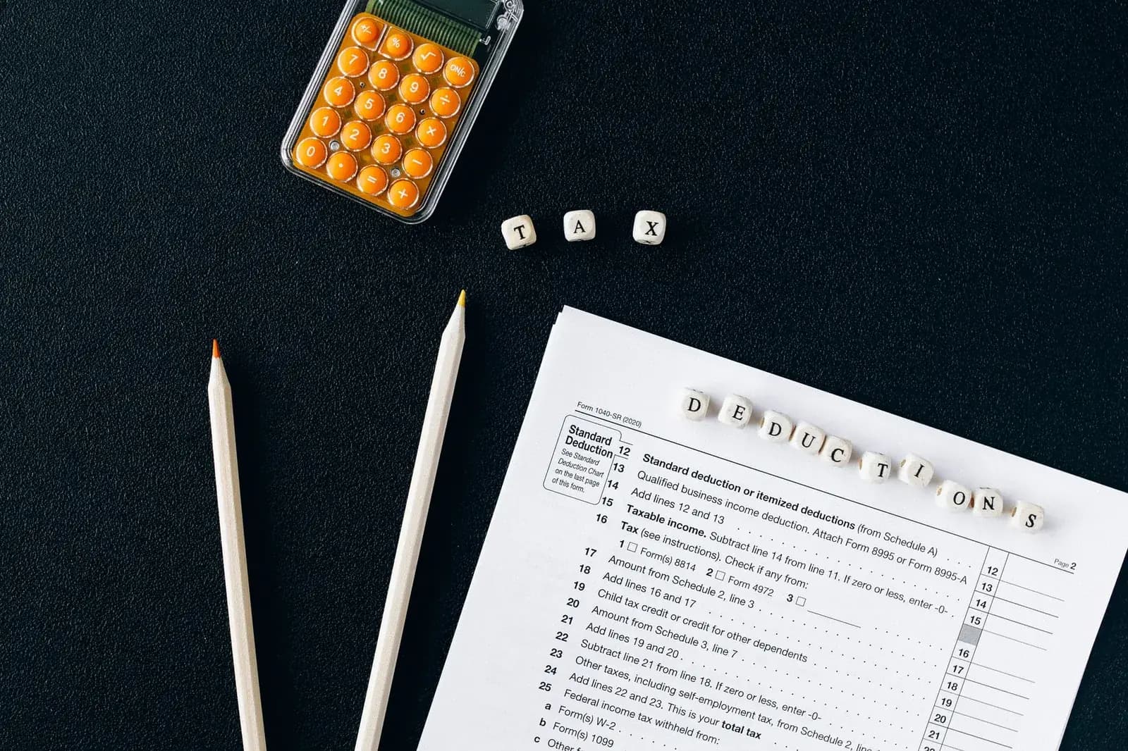 Formulaire de déclaration fiscale, calculatrice orange et crayons posés sur un bureau