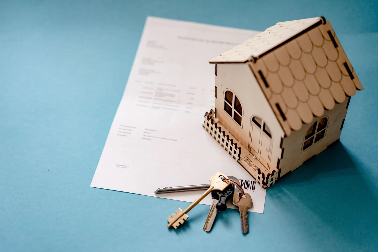 Maquette de maison en bois et trousseau de clés posés sur un contrat de vente