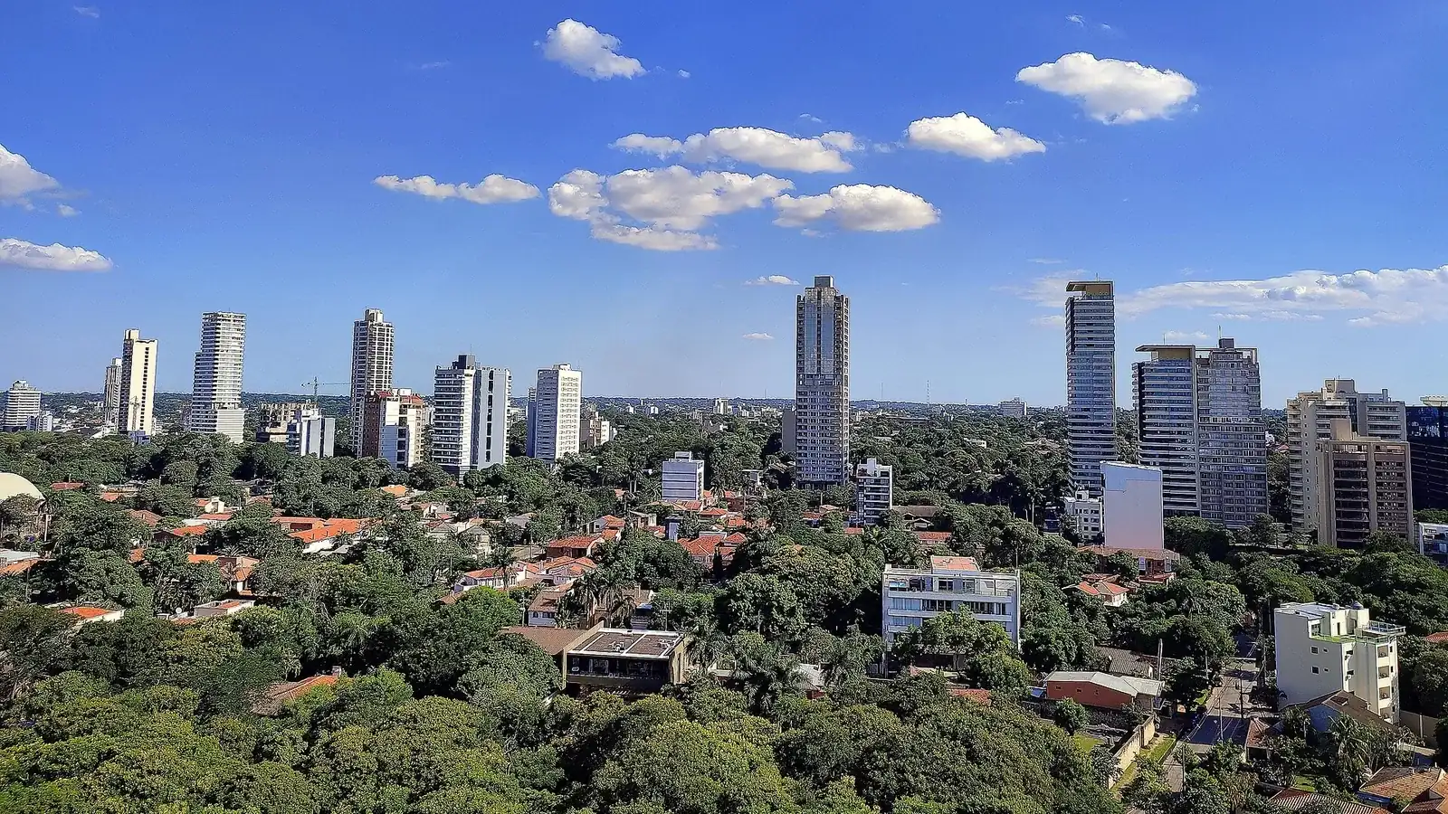 Tours d'habitation et maisons à toits de tuiles parmi les arbres, dans un quartier résidentiel d'Asunción