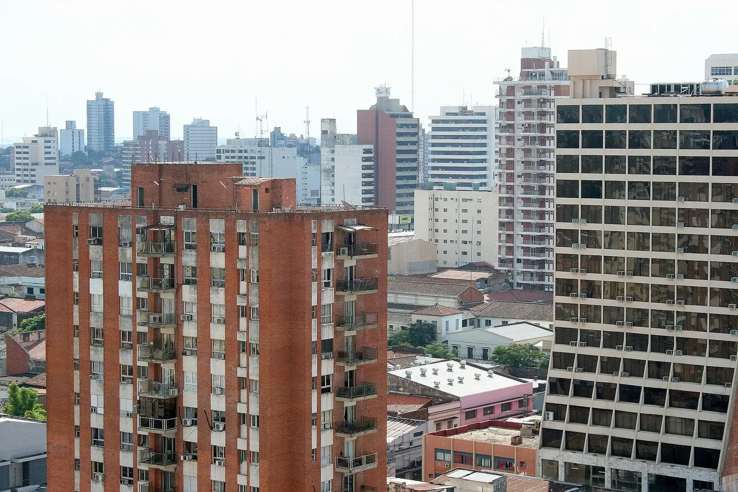 Tours d'appartements et immeubles de bureaux dans le centre d'Asunción, avec des toits de maisons basses au premier plan