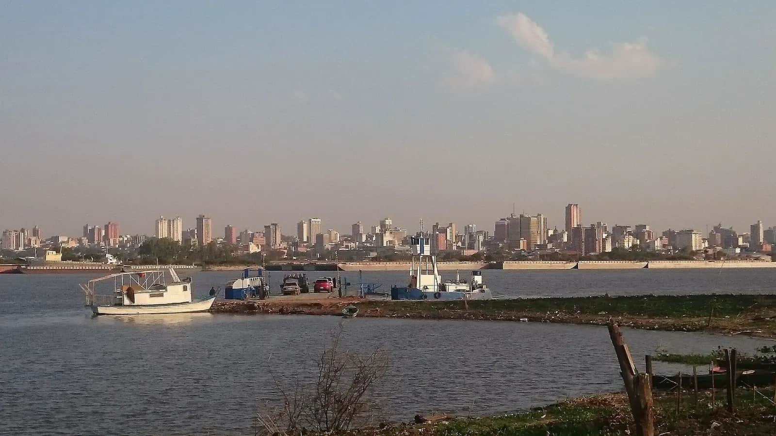 Le río Paraguay depuis la rive du Chaco à Chaco’í, avec un bac et les immeubles d’Asunción sur l’autre rive
