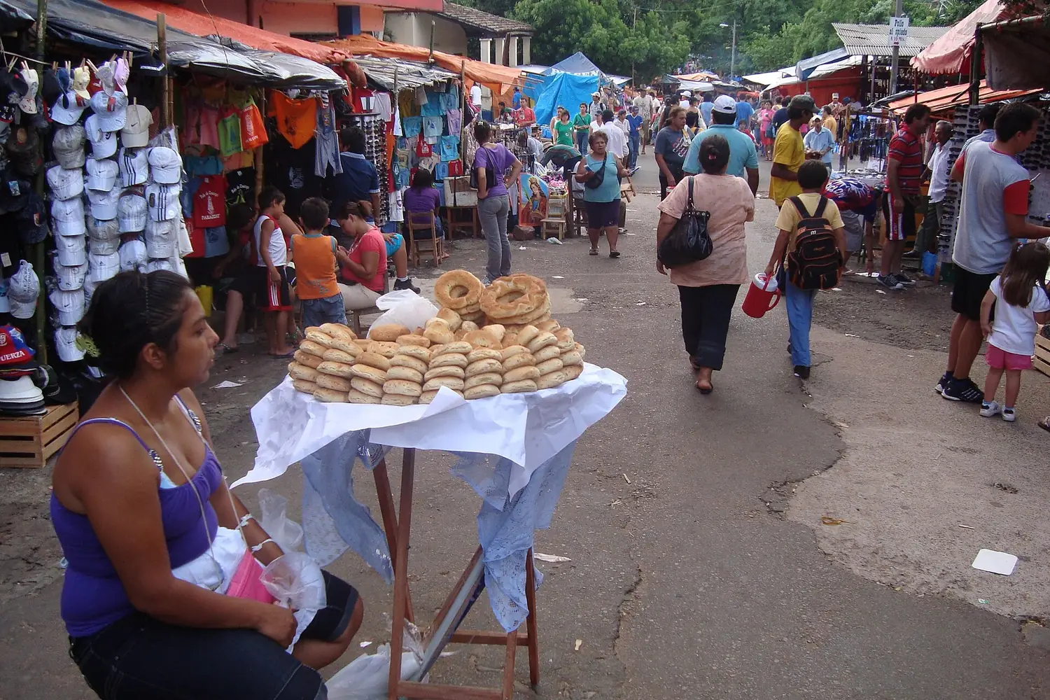 Vendeuse de chipa (chipera) assise près de sa table de chipas dans une allée du marché de Caacupé, Paraguay
