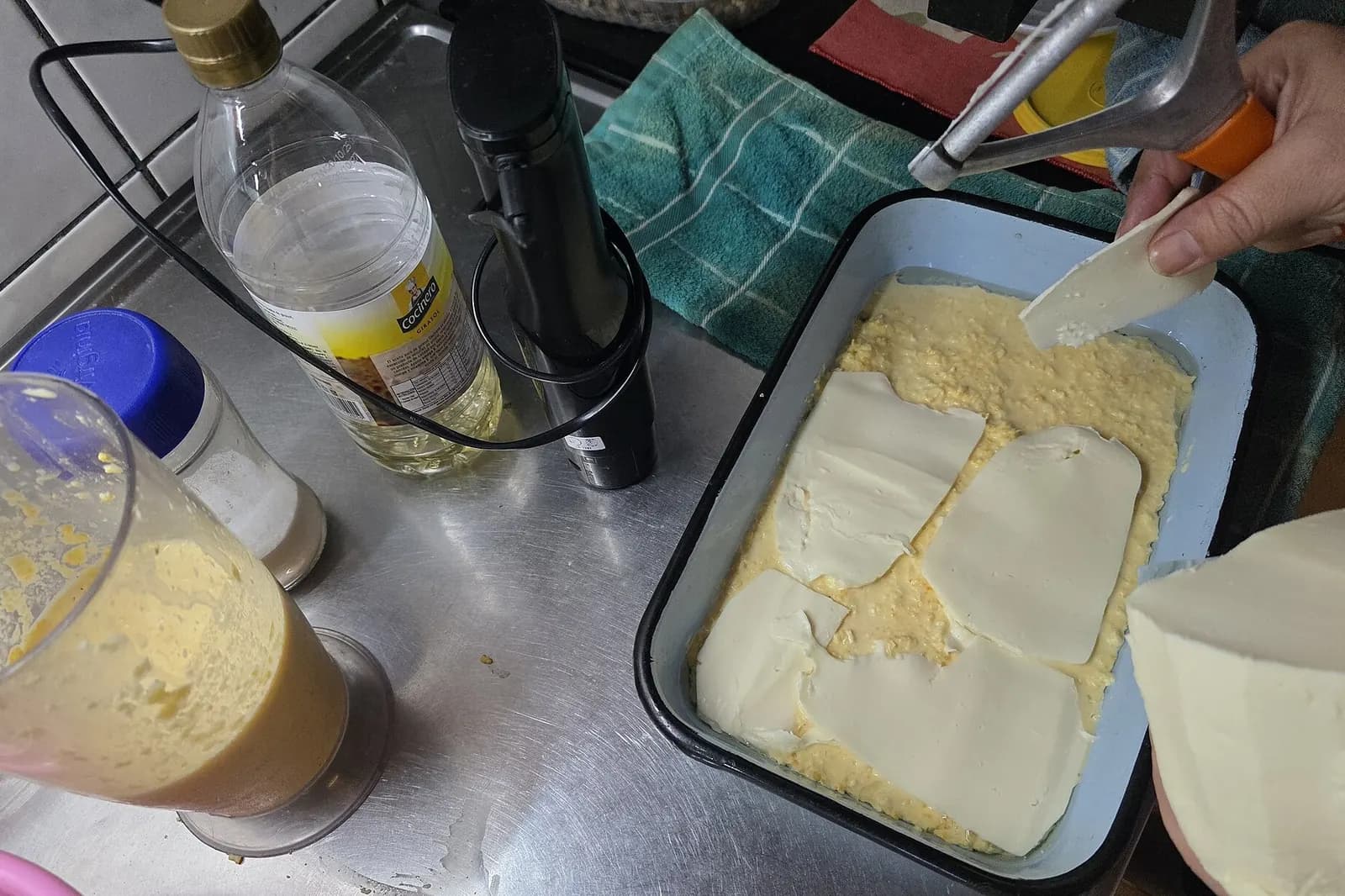 Préparation d'un chipa guazú : appareil de maïs mixé versé dans un plat à four, tranches de fromage frais posées dessus