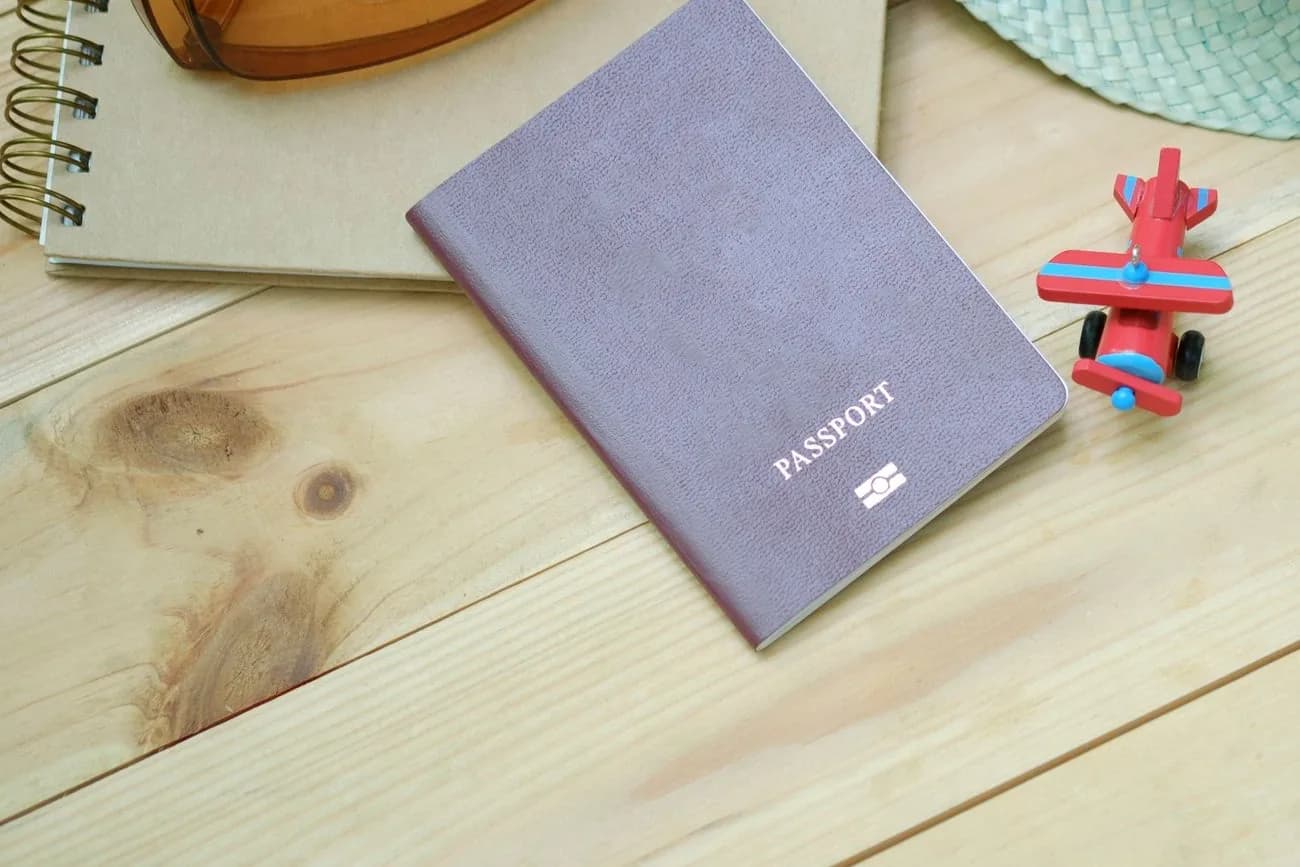 Passeport posé sur un bureau en bois, à côté d'un carnet, pour préparer un dossier de résidence