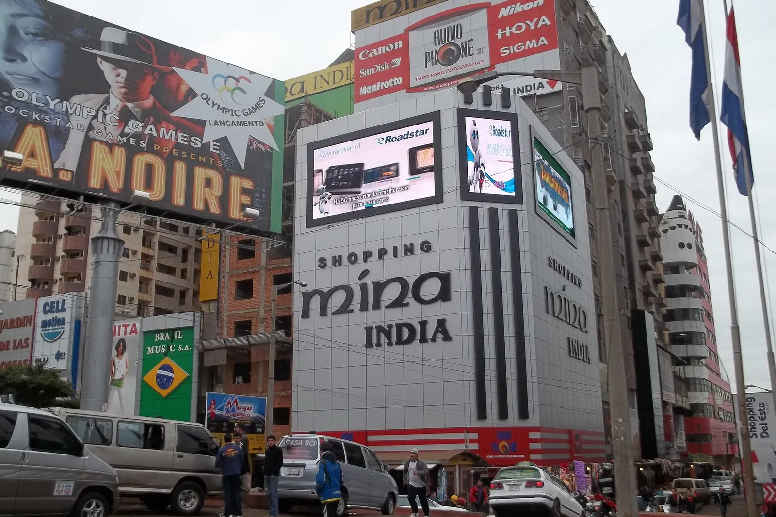 Rue commerçante du centre de Ciudad del Este, devant la galerie Shopping Mina India, ses enseignes lumineuses, ses panneaux publicitaires et les minibus