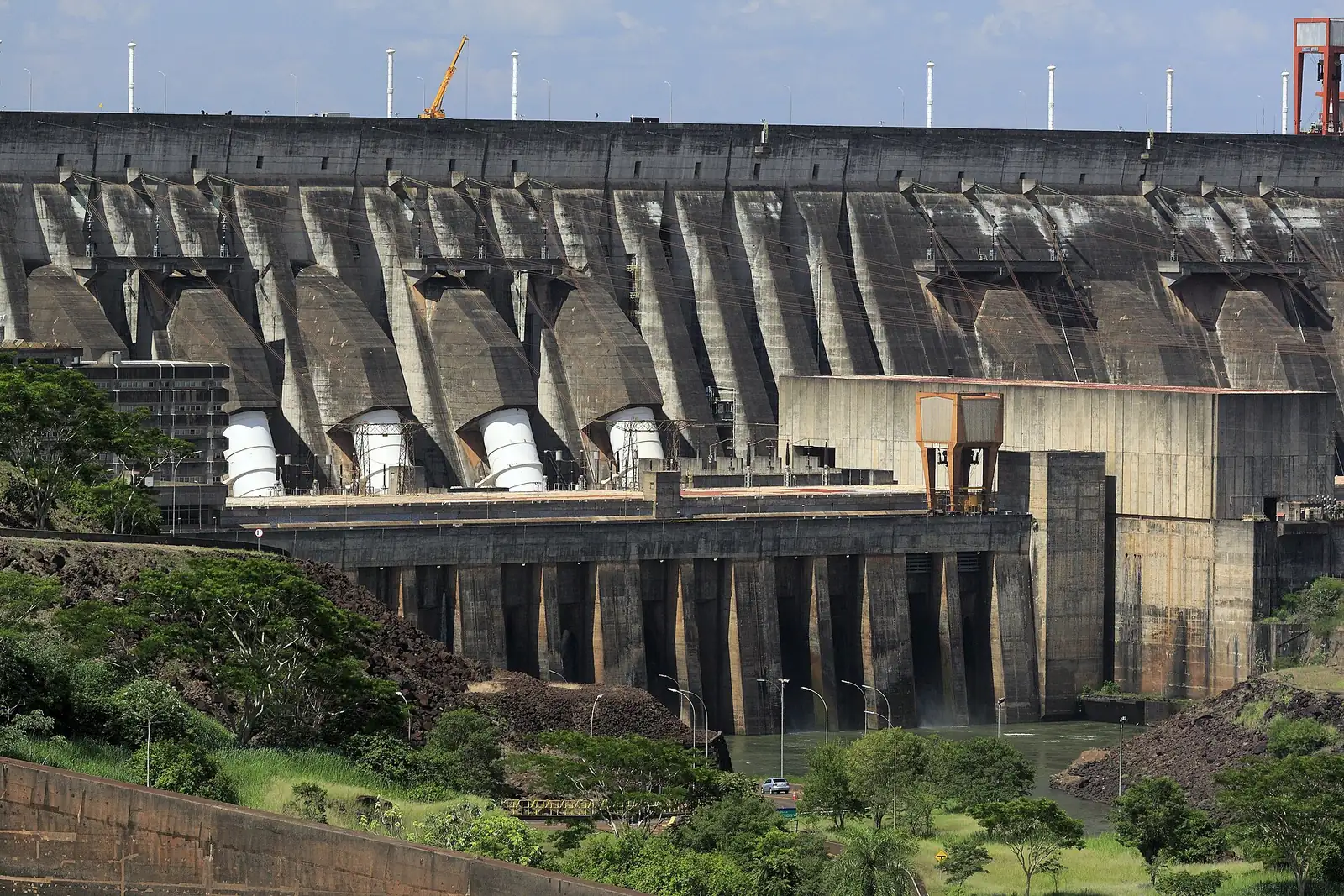 La façade de la centrale d'Itaipú avec ses conduites forcées blanches et la crête du barrage, vue depuis le belvédère côté paraguayen