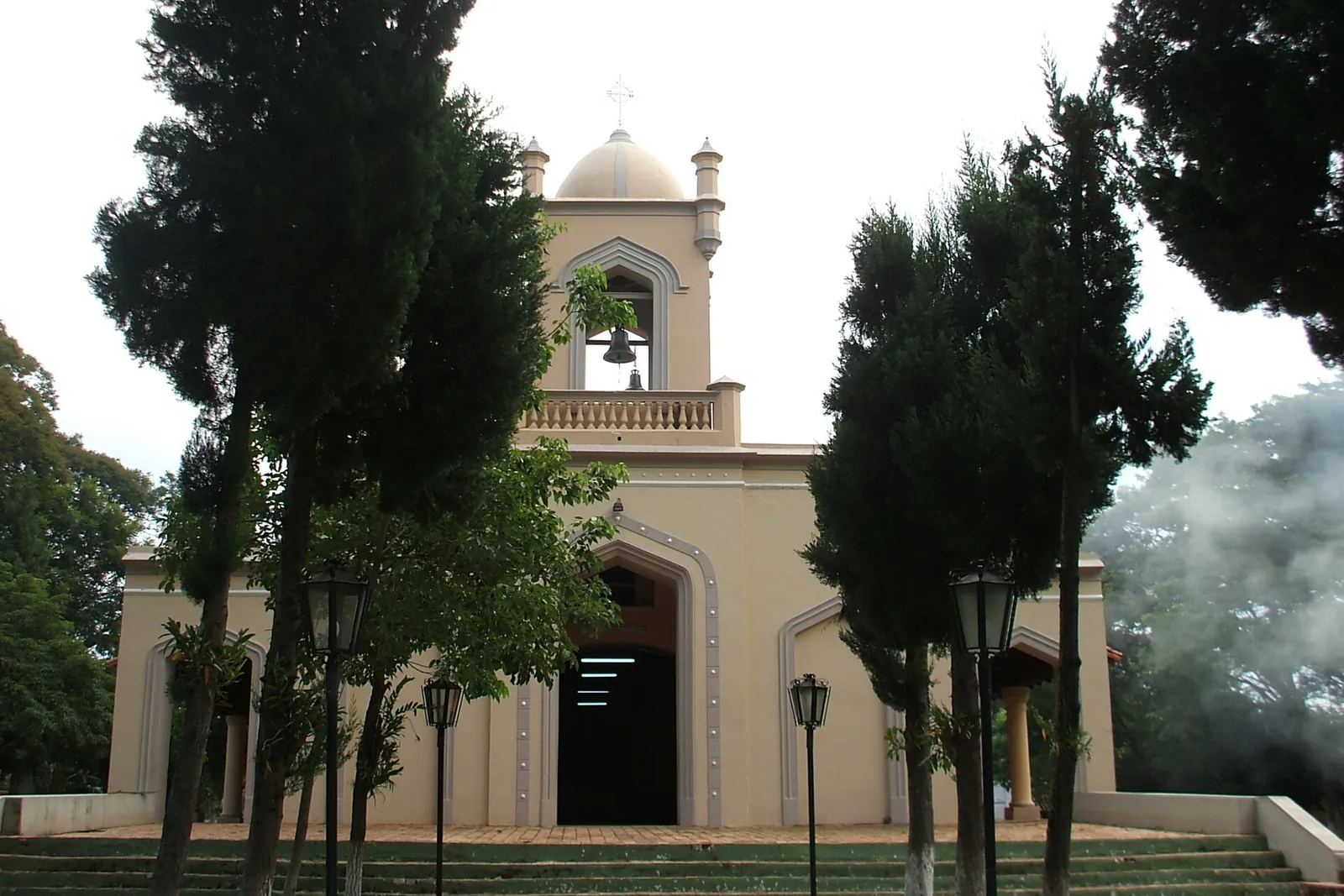 Façade de l’église d’Altos, dans le département de la Cordillera, avec son clocher et son escalier entre les cyprès