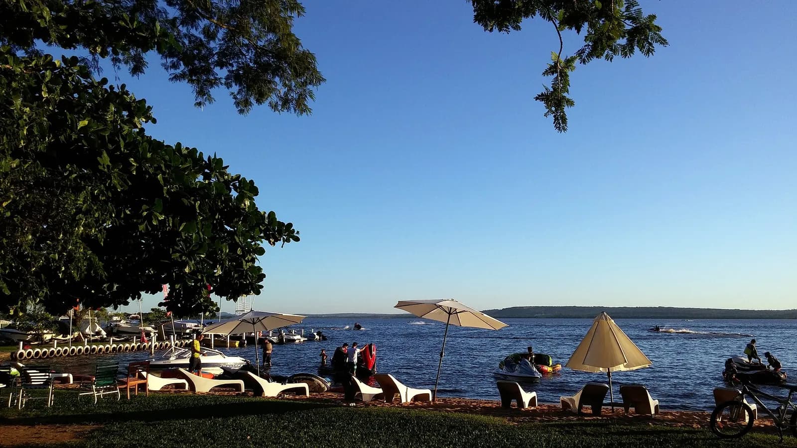 Rive du lac Ypacaraí à San Bernardino : parasols, transats, jet-skis et baigneurs sous un ciel bleu