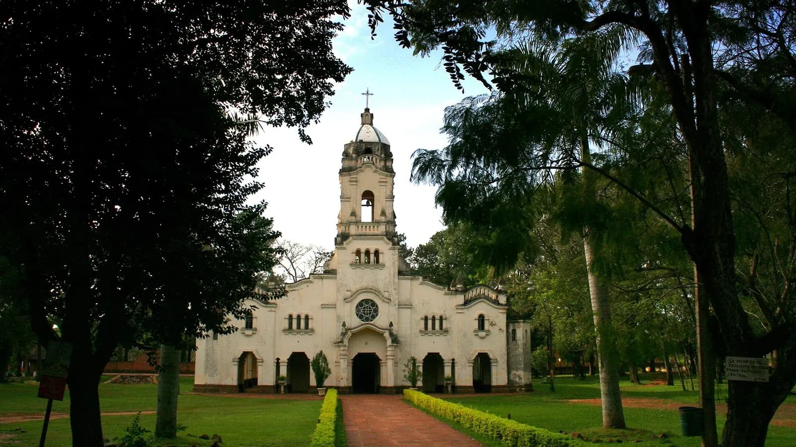 Église blanche de San Ignacio Guazú au bout d'une allée de briques, entre de grands arbres, dans le département de Misiones, ancienne réduction jésuite