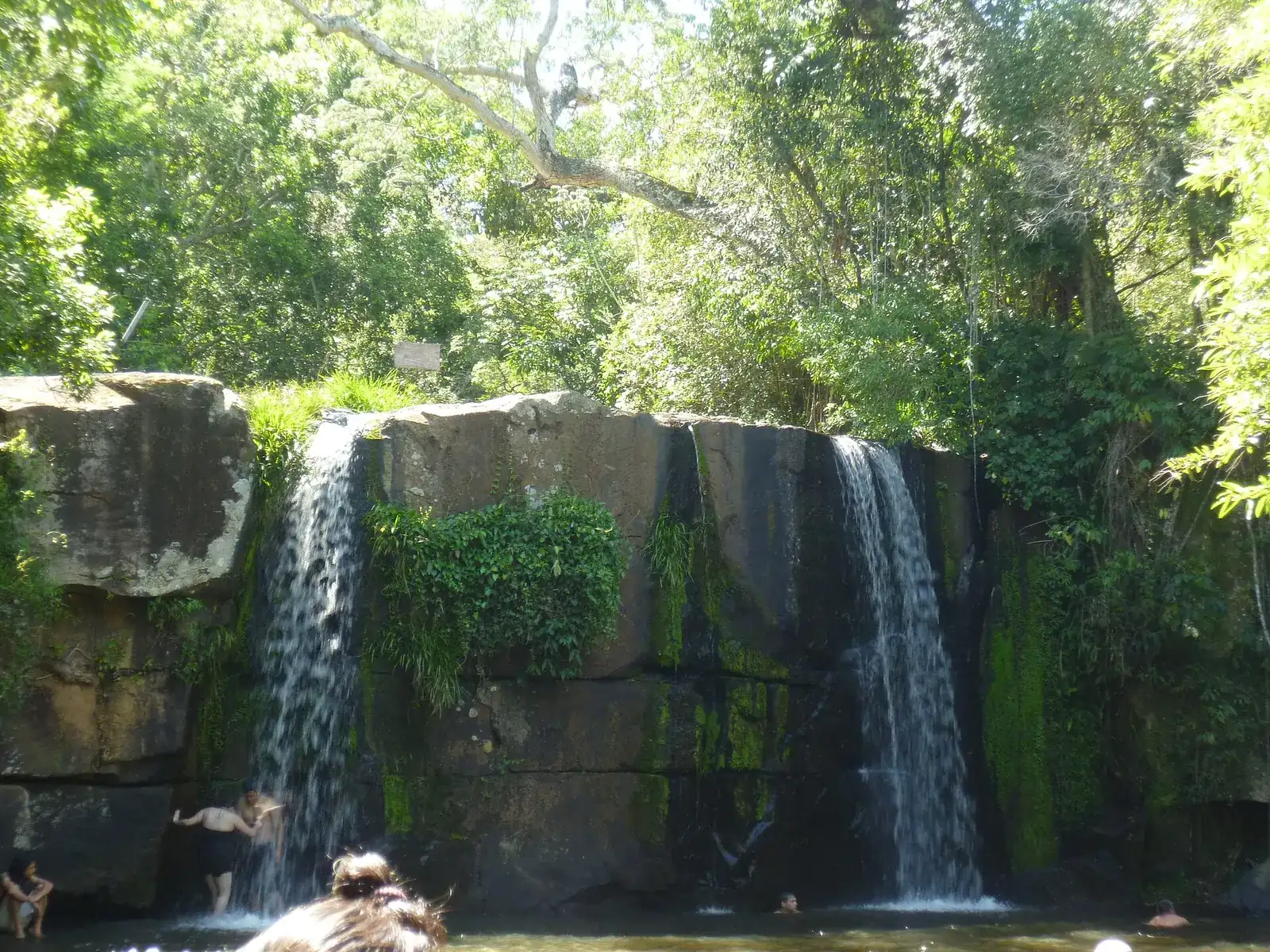 Cascade du Salto Cristal dans le parc national d'Ybycuí, entre rochers et forêt, avec quelques baigneurs au pied